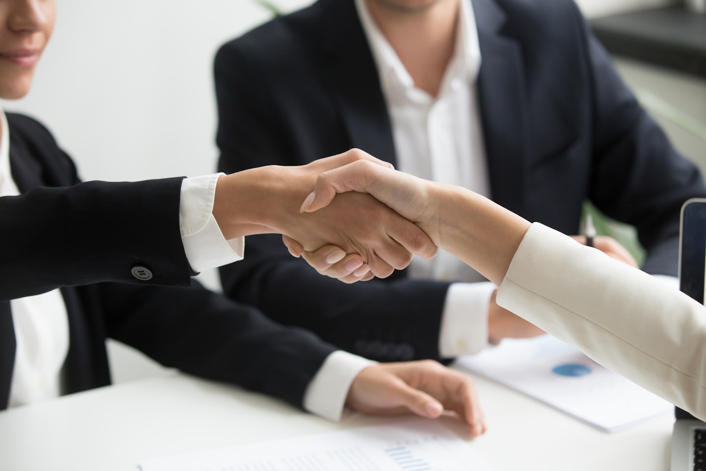 Due professionisti si stringono la mano su una scrivania in un ufficio.